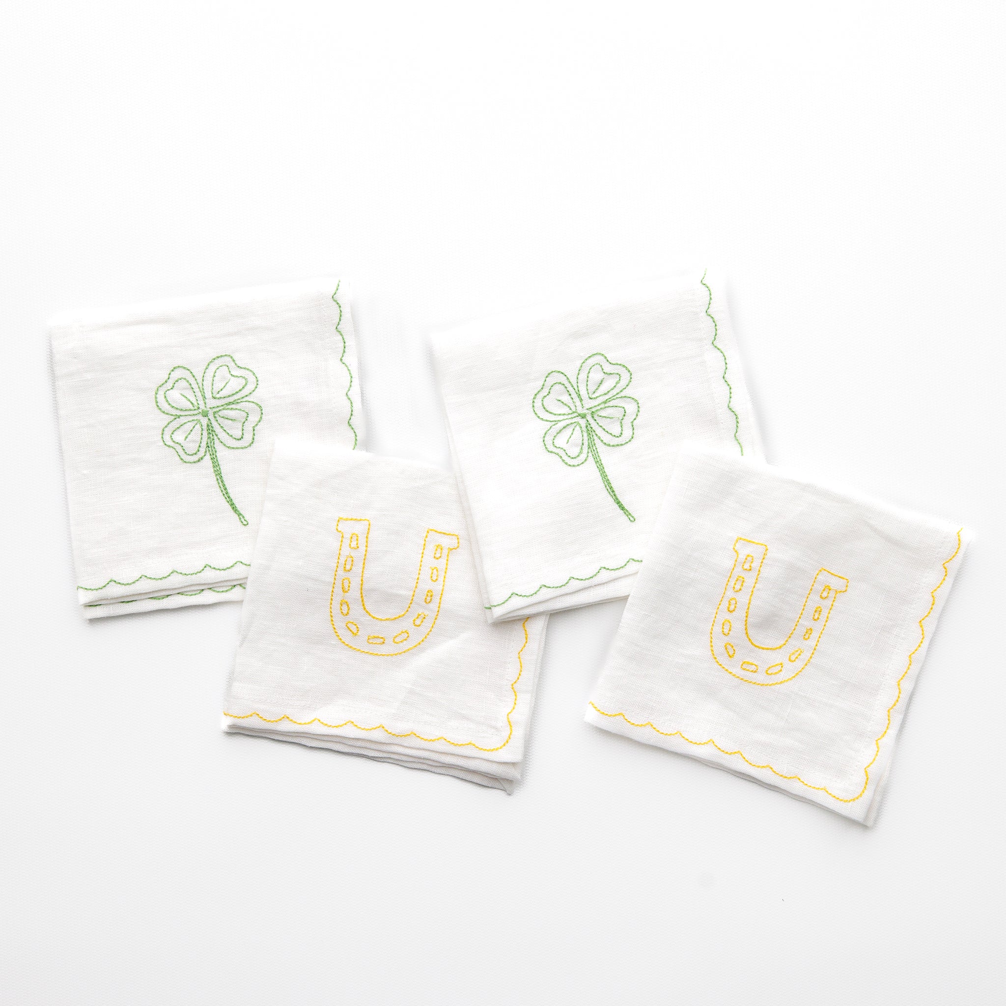 White linen cocktail napkins embroidered with green 4 leaf clover and lucky horse shoe designs