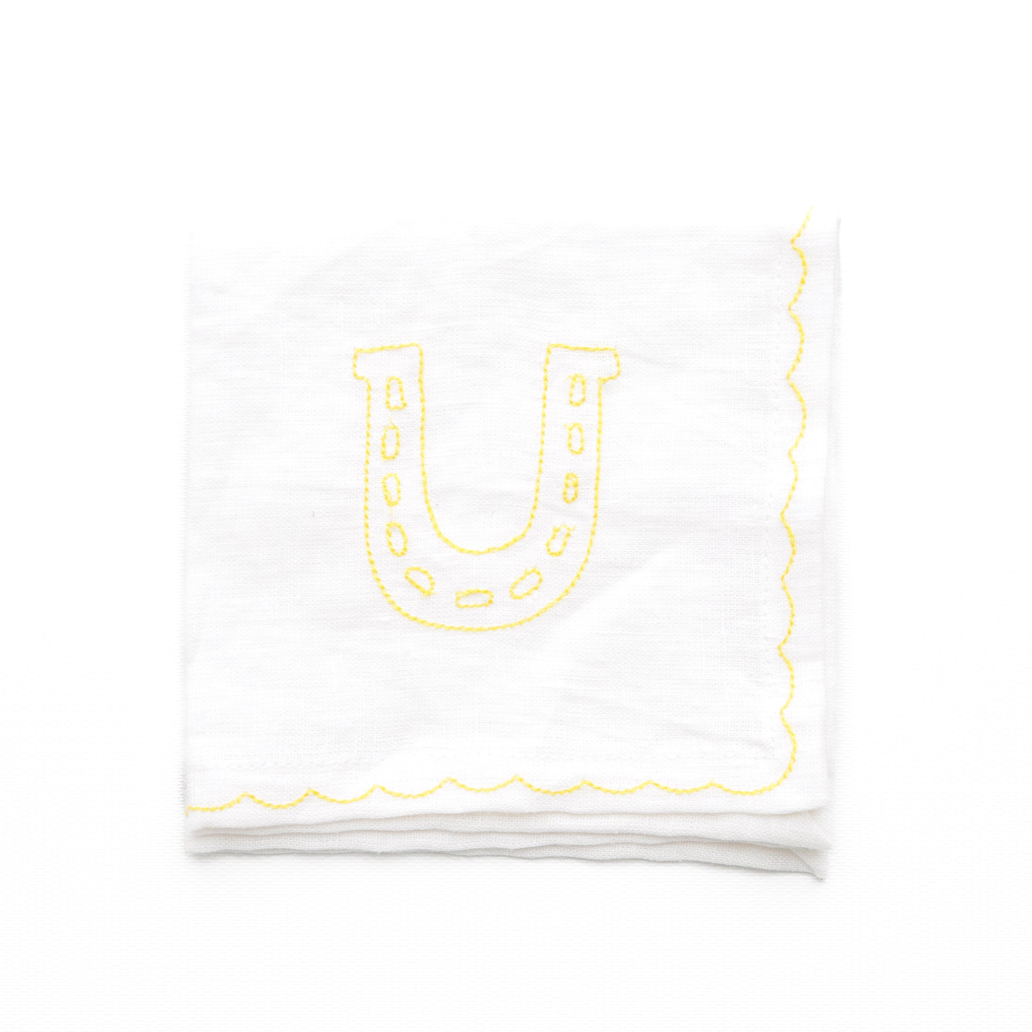 White linen cocktail napkins embroidered with lucky horse shoe design