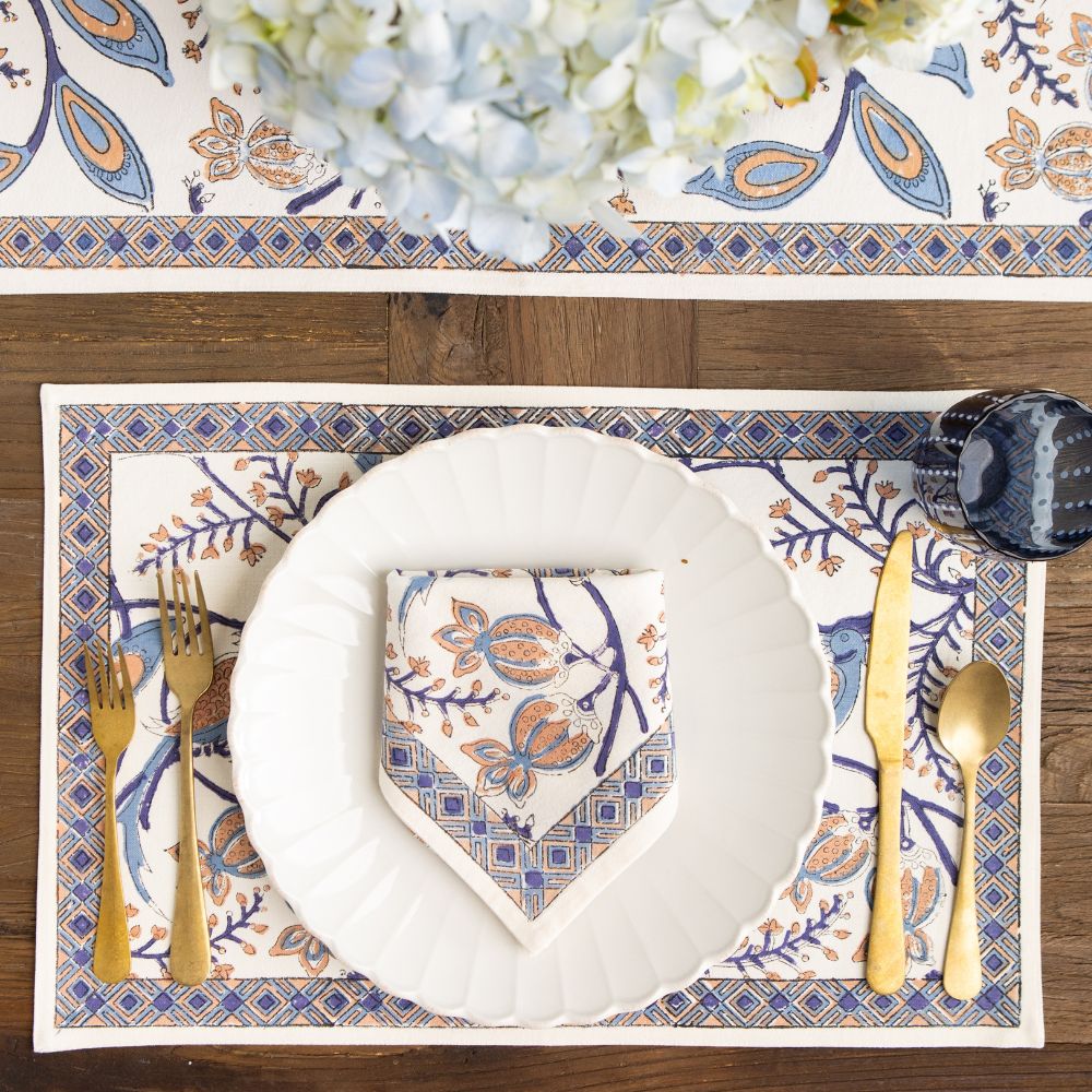 Elegant table setting with patterned placemat, plate, and cutlery on a wooden table.