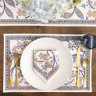Elegant table setting with patterned placemat, plate, and cutlery on a wooden table.