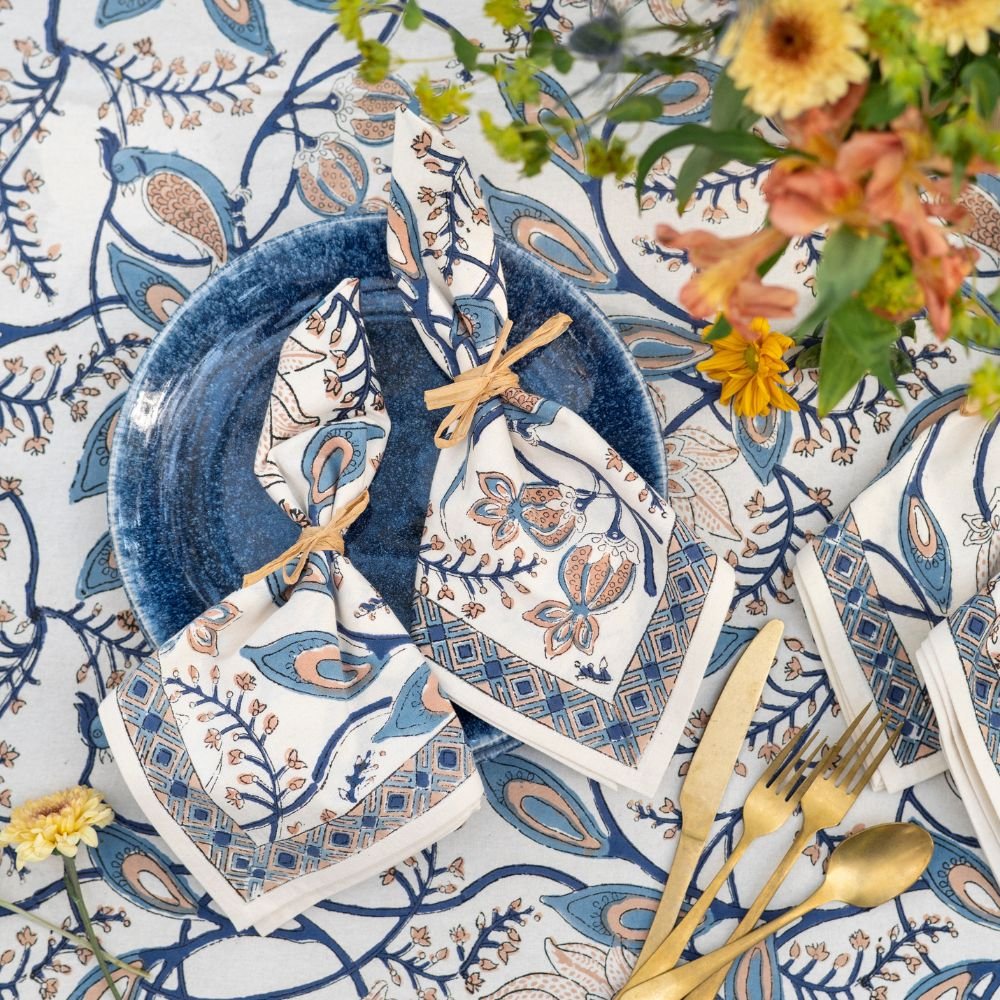 Decorative table setting with blue and white patterned plates, gold cutlery, and flowers.