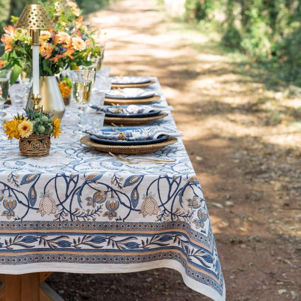 Elegant outdoor table setting with floral tablecloth and decorations.
