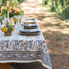 Elegant outdoor table setting with floral tablecloth and decorations.