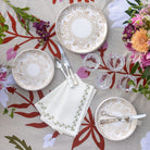Decorative table setting with floral tablecloth, plates, cutlery, and napkins.