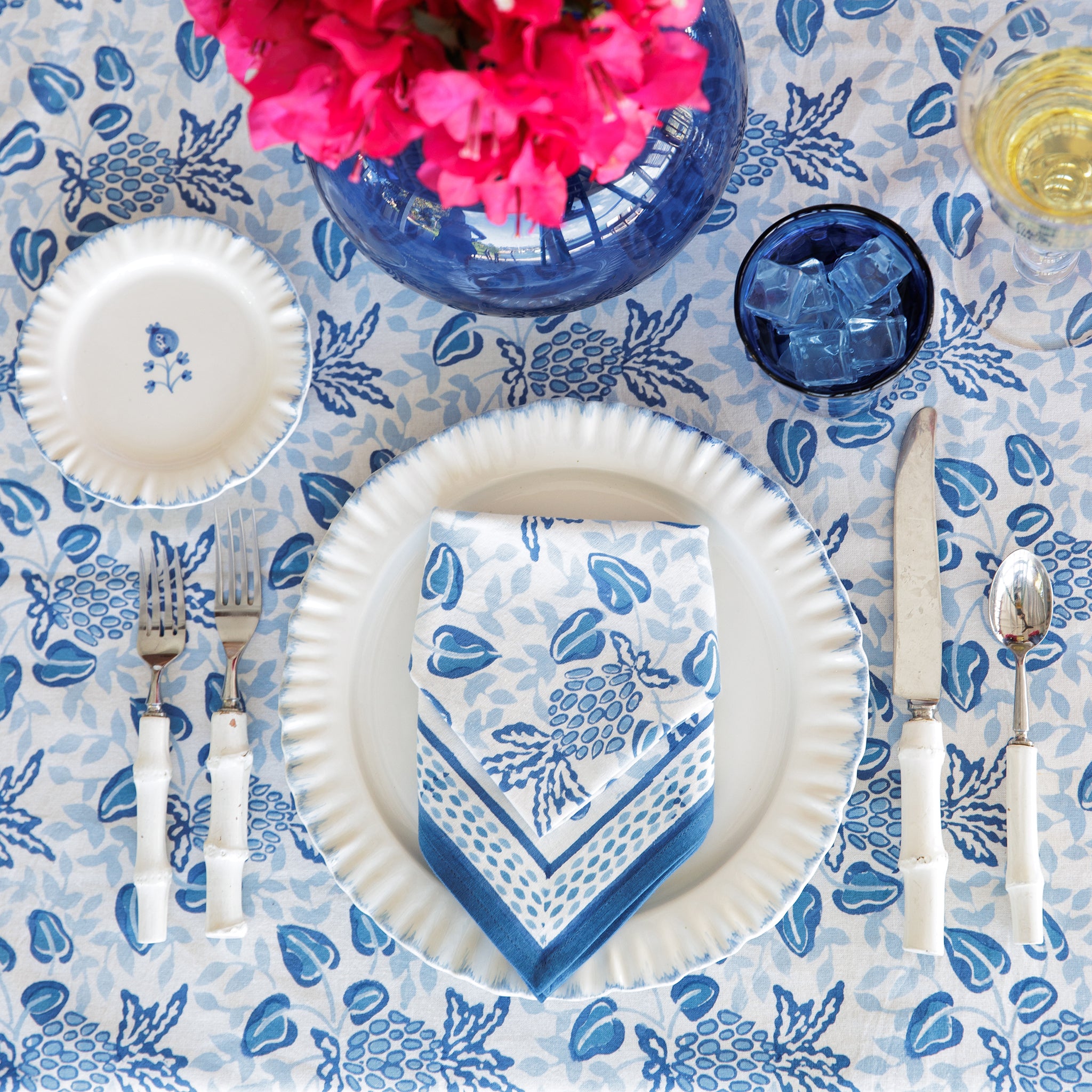 A set of blue and white floral patterned napkins displayed on a table setting with plates and cutlery.