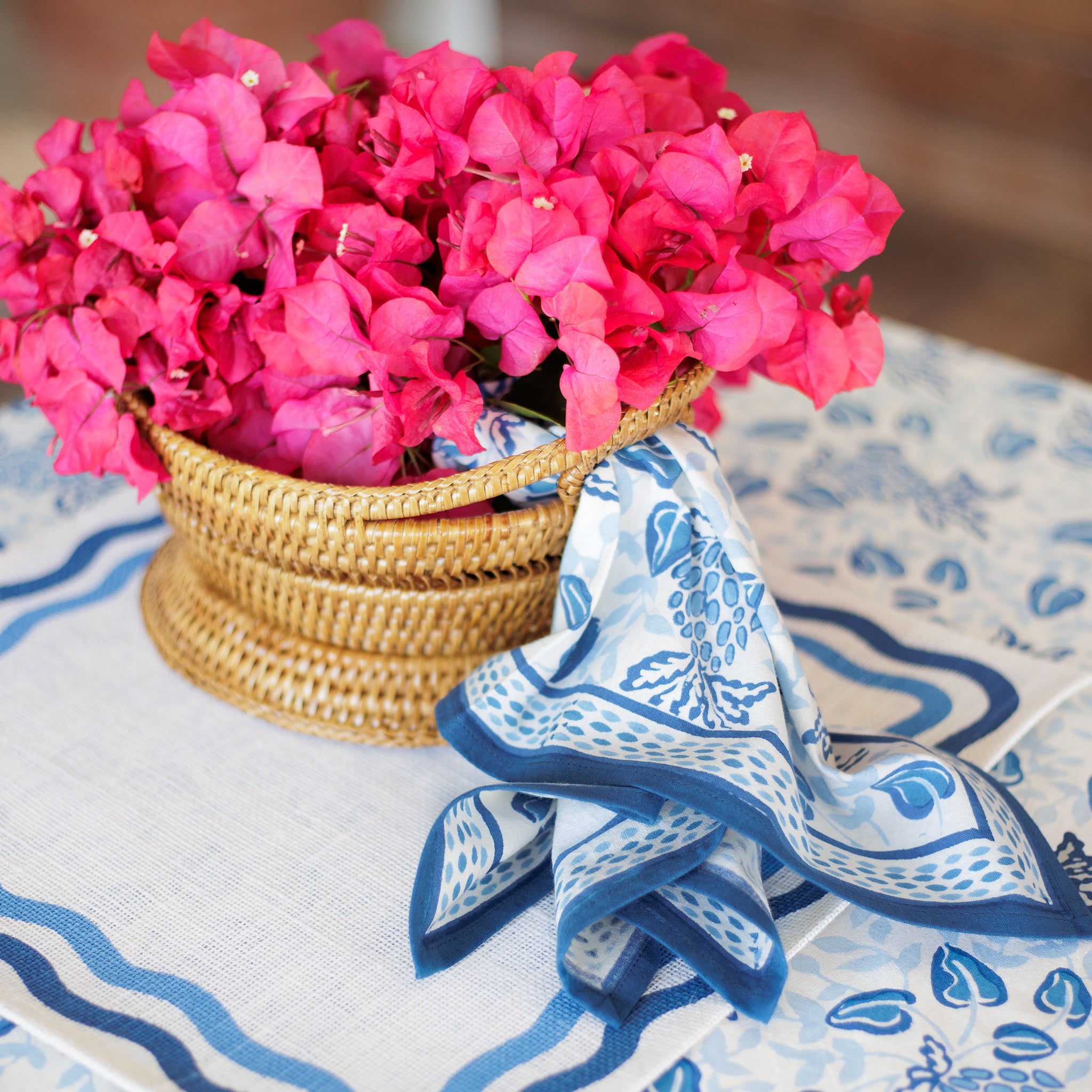Blue and white table linens with a woven basket and pink flowers.