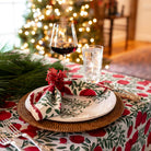 A Christmas table setting featuring pomegranate napkins and a tablecloth.