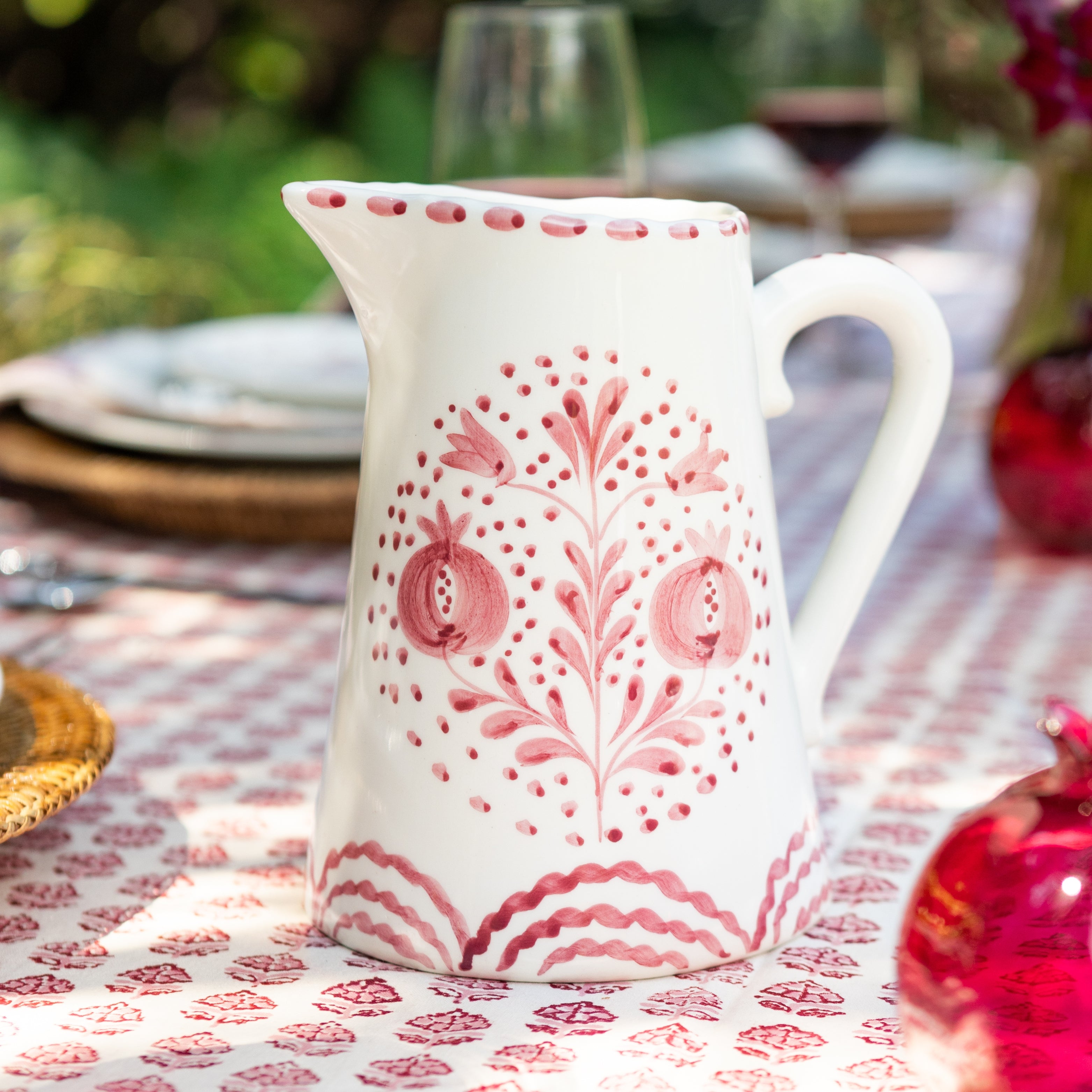 White ceramic pitcher with rose floral patterns on a tablecloth with similar design