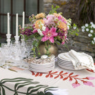 Decorated table with floral centerpiece, plates, and cutlery on a patterned tablecloth.