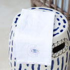 A linen tea towel with embroidered design featuring a moon with an eye symbol