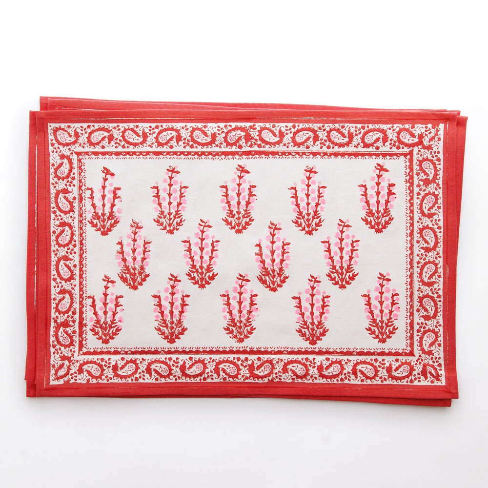 A set of red and white placemats with a floral pattern and paisley border