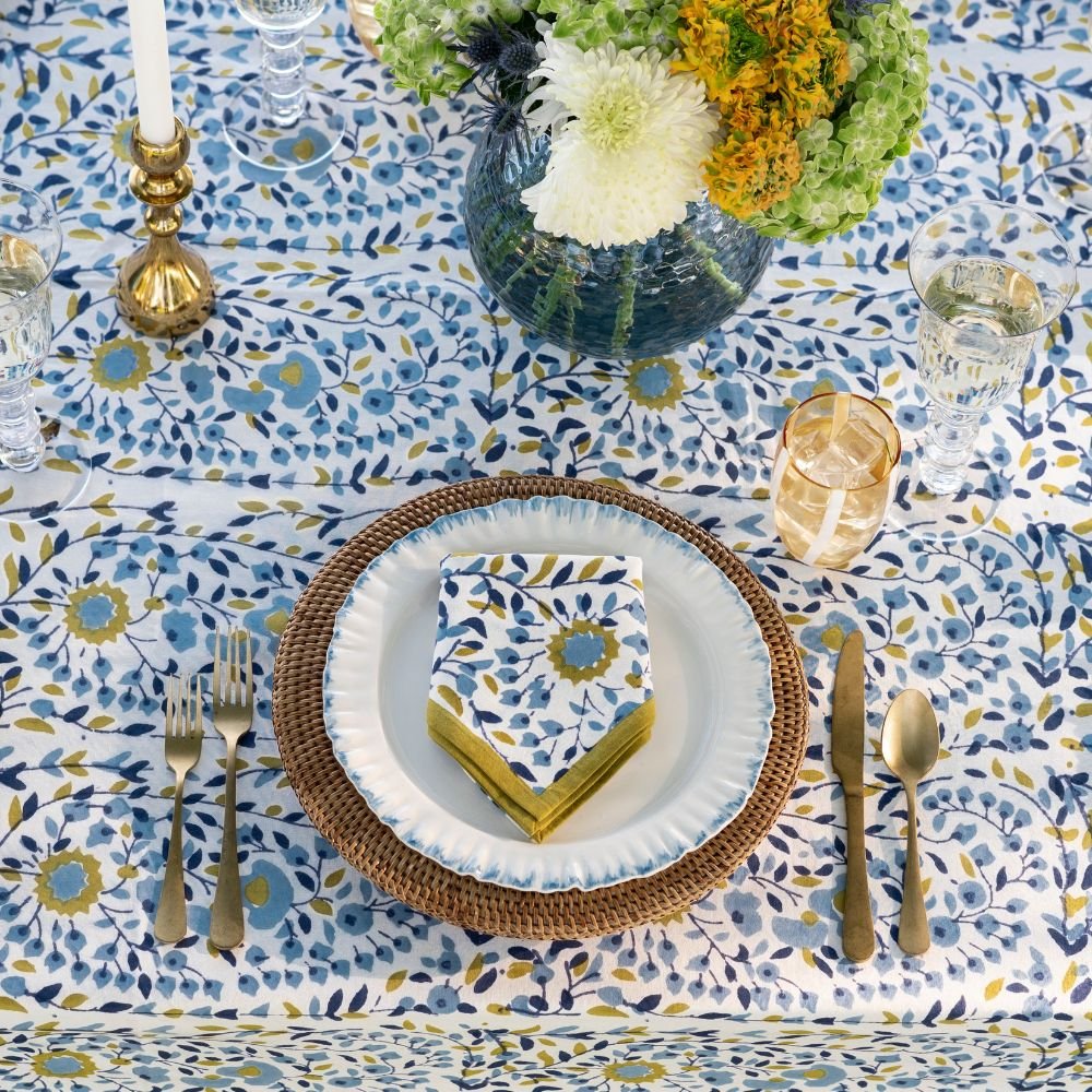 Elegant table setting with floral tablecloth, plates, cutlery, and napkin.