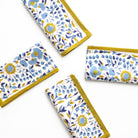 Set of floral-patterned napkins with yellow edges on a white background