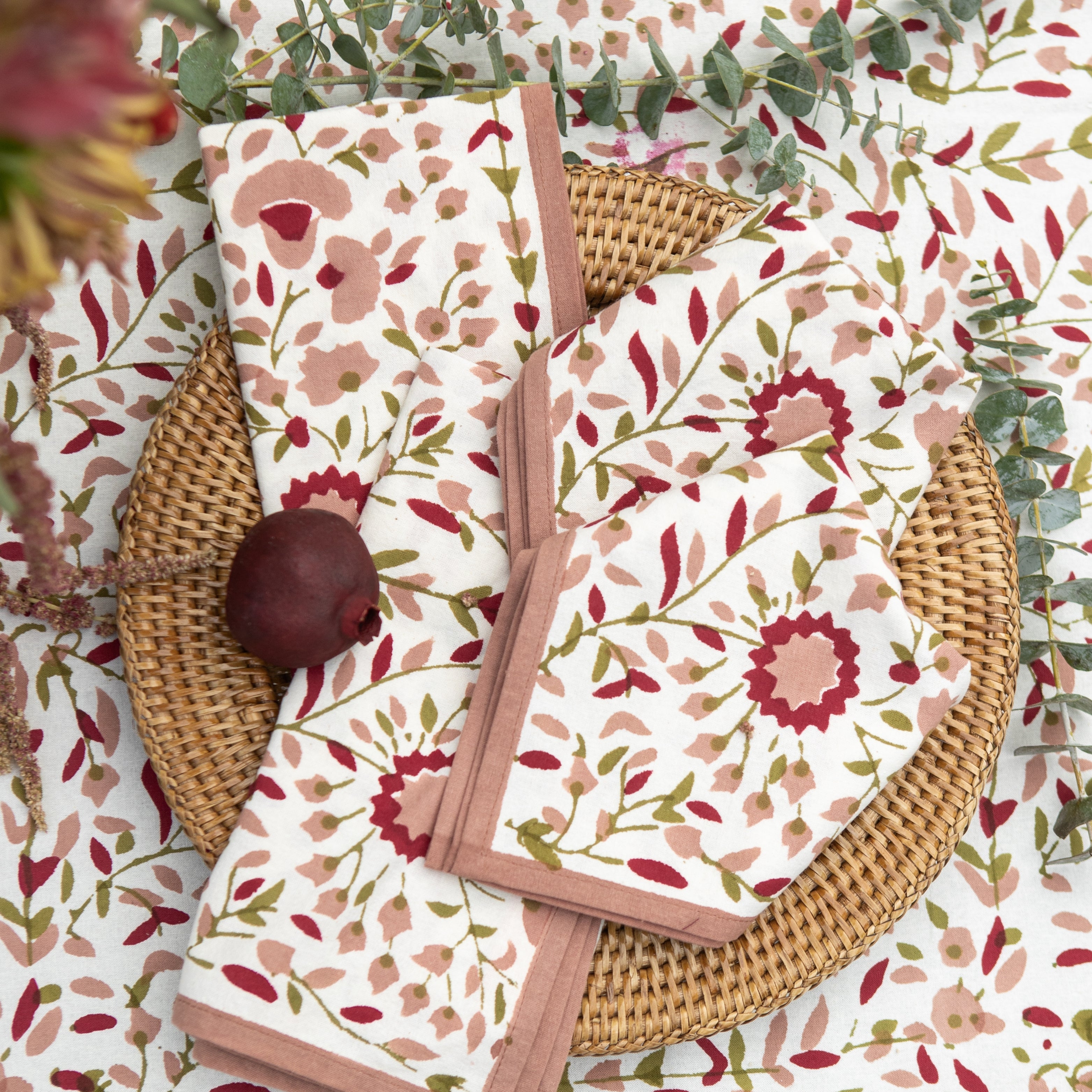 Floral-patterned napkins on a matching floral tablecloth with wicker charger.