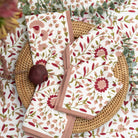 Floral-patterned napkins on a matching floral tablecloth with wicker charger.