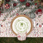 Decorative table setting with floral tablecloth, woven charger, and patterned plate.