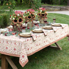 Decorated outdoor table with floral arrangements and tablecloth in a garden setting