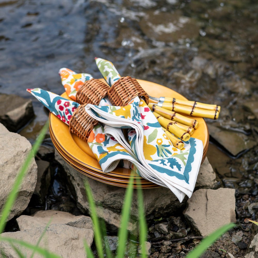 Teal and yellow napkins with woven napkin rings and bamboo cutlery