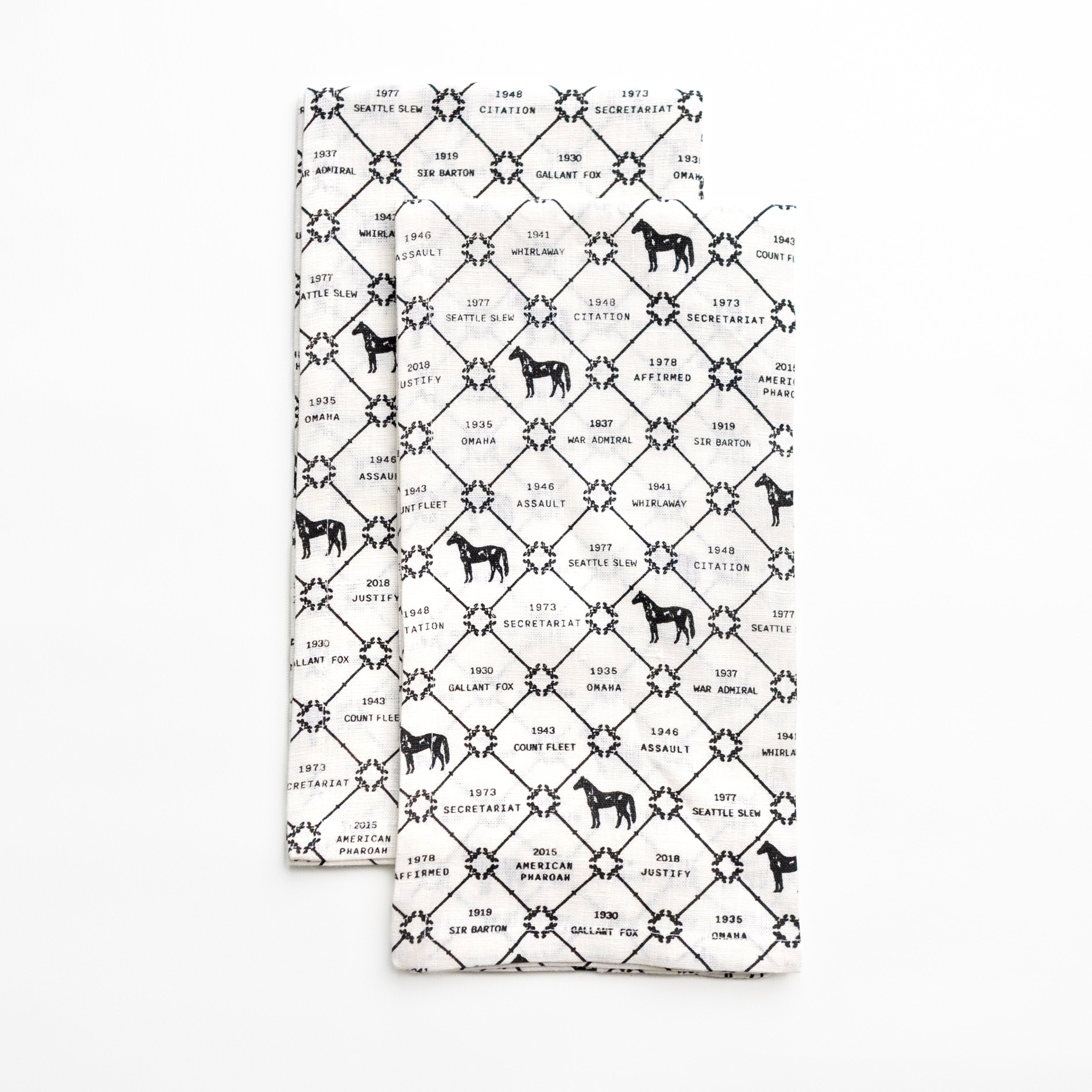 Two folded tea towels with black and white pattern on a white background