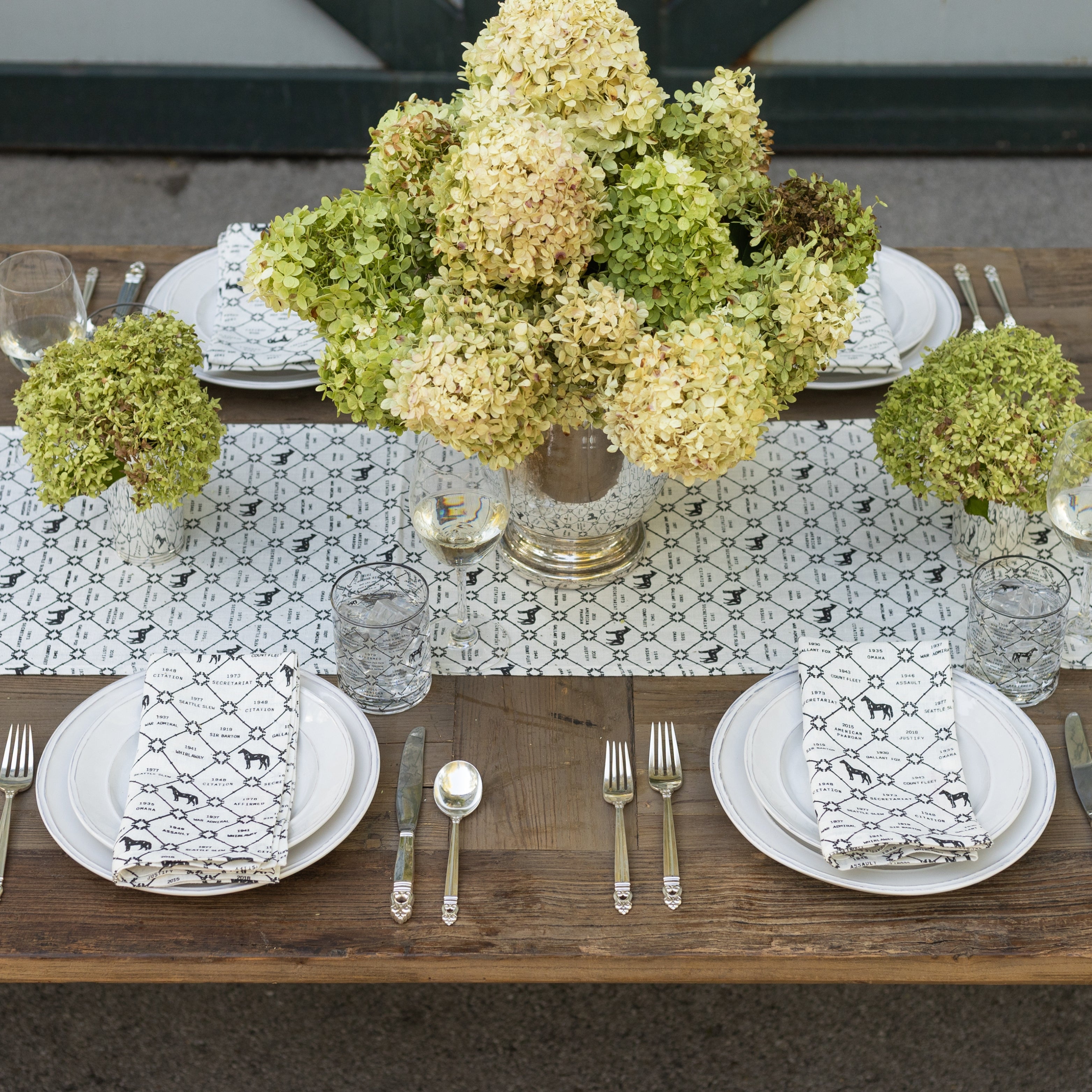 Elegant table setting with floral centerpieces, plates, and cutlery on a wooden table.