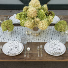 Elegant table setting with floral centerpieces, plates, and cutlery on a wooden table.