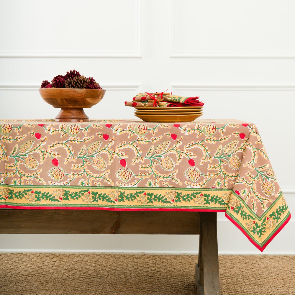A rectangular tablecloth with a pinecone and foliage pattern, displayed on a table with a white background
