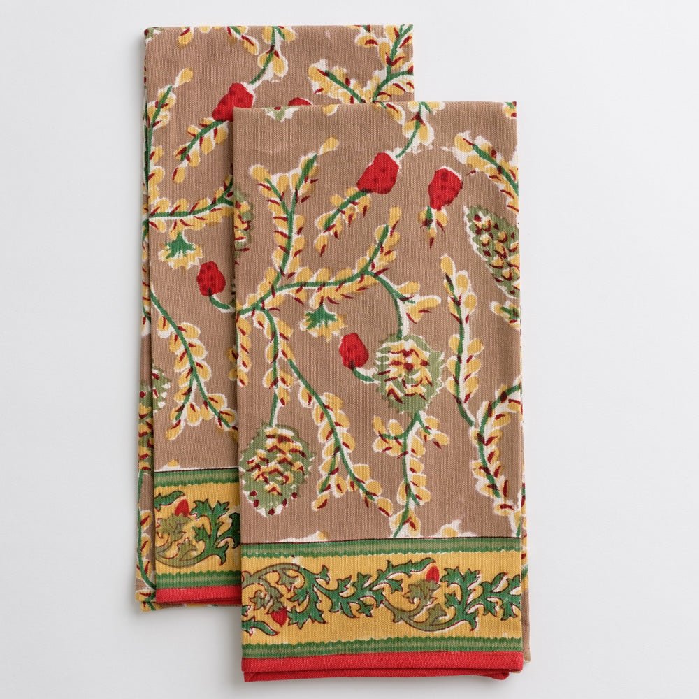 Two cotton tea towels with a hand block printed pinecone motif, greenery, and a red border.