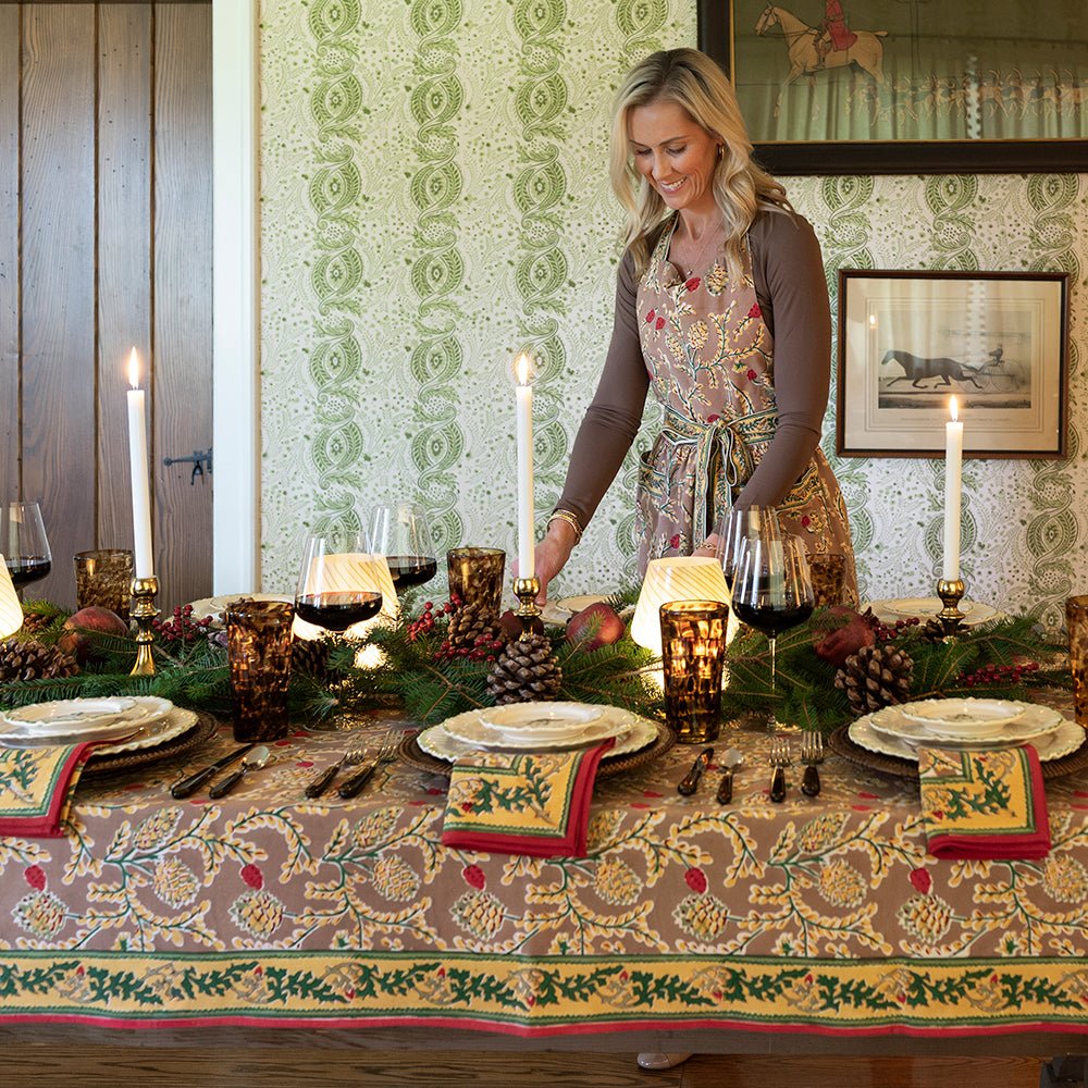 A rectangular tablecloth with a pinecone and foliage pattern, displayed on a table set for dining indoors