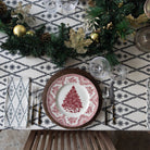 A table setting featuring a geometric patterned tablecloth, arranged with plates, cutlery, and greenery.