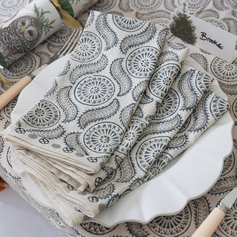 A set of folded cloth napkins with a geometric pattern, displayed on a table with other tableware.