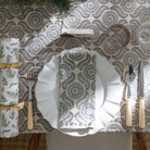 A table setting featuring a tablecloth and napkin with a geometric pattern, displayed on a table with other tableware.