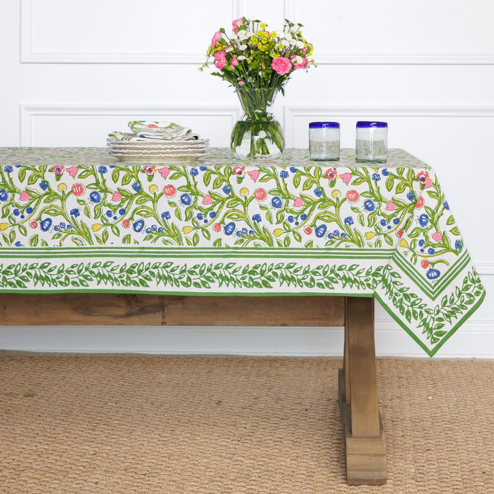 A colorful floral tablecloth with yellow, blue, and red flowers displayed on a table.
