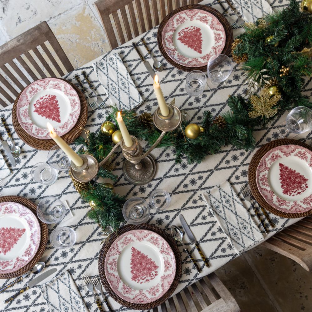 A table setting featuring a geometric patterned tablecloth, arranged with plates, cutlery, and candles.