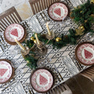 A table setting featuring a geometric patterned tablecloth, arranged with plates, cutlery, and candles.