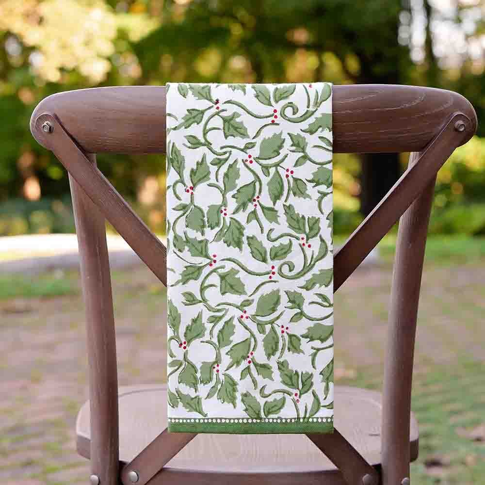 A cotton tea towel with a holly berry design hanging on a wooden chair