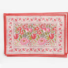 A rectangular placemat with a floral pattern featuring various shades of pink and green, bordered with a red line.