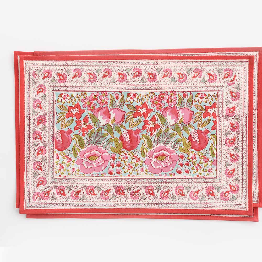 A rectangular placemat with a floral pattern featuring various shades of pink and green, bordered with a red line.