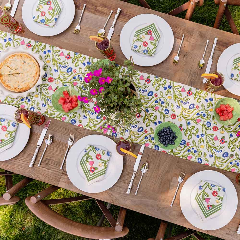Close up of Emma table runner on dinner table decorated with basket and green centerpiece. 