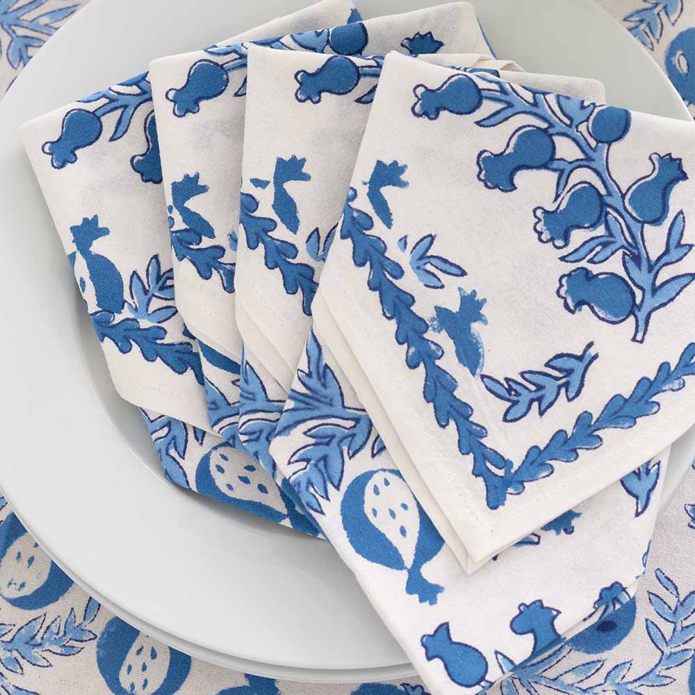 Folded set of 4 napkins on a white plate.
