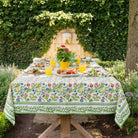 A colorful floral tablecloth with yellow, blue, and red flowers displayed on a table outdoors.