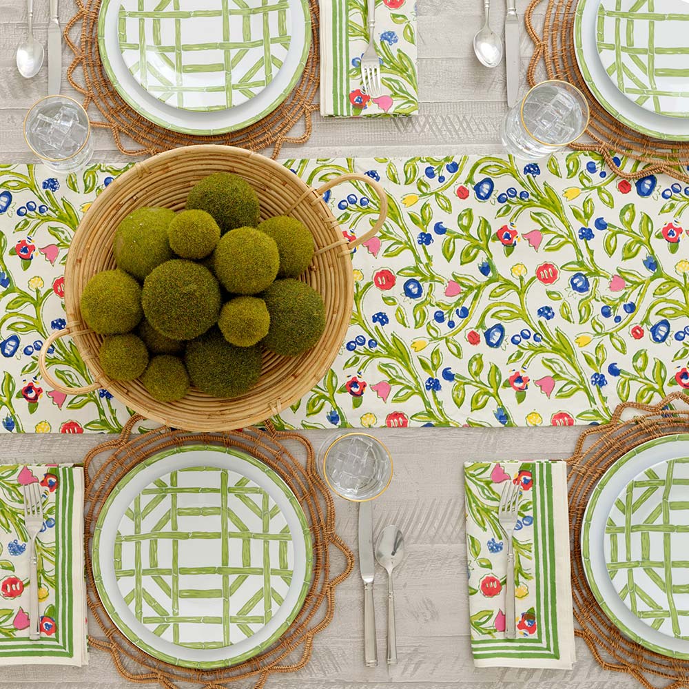Close up of Emma table runner on dinner table decorated with basket and green centerpiece.