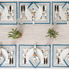 Dinner table with matching placemats and napkins with plants as centerpieces.