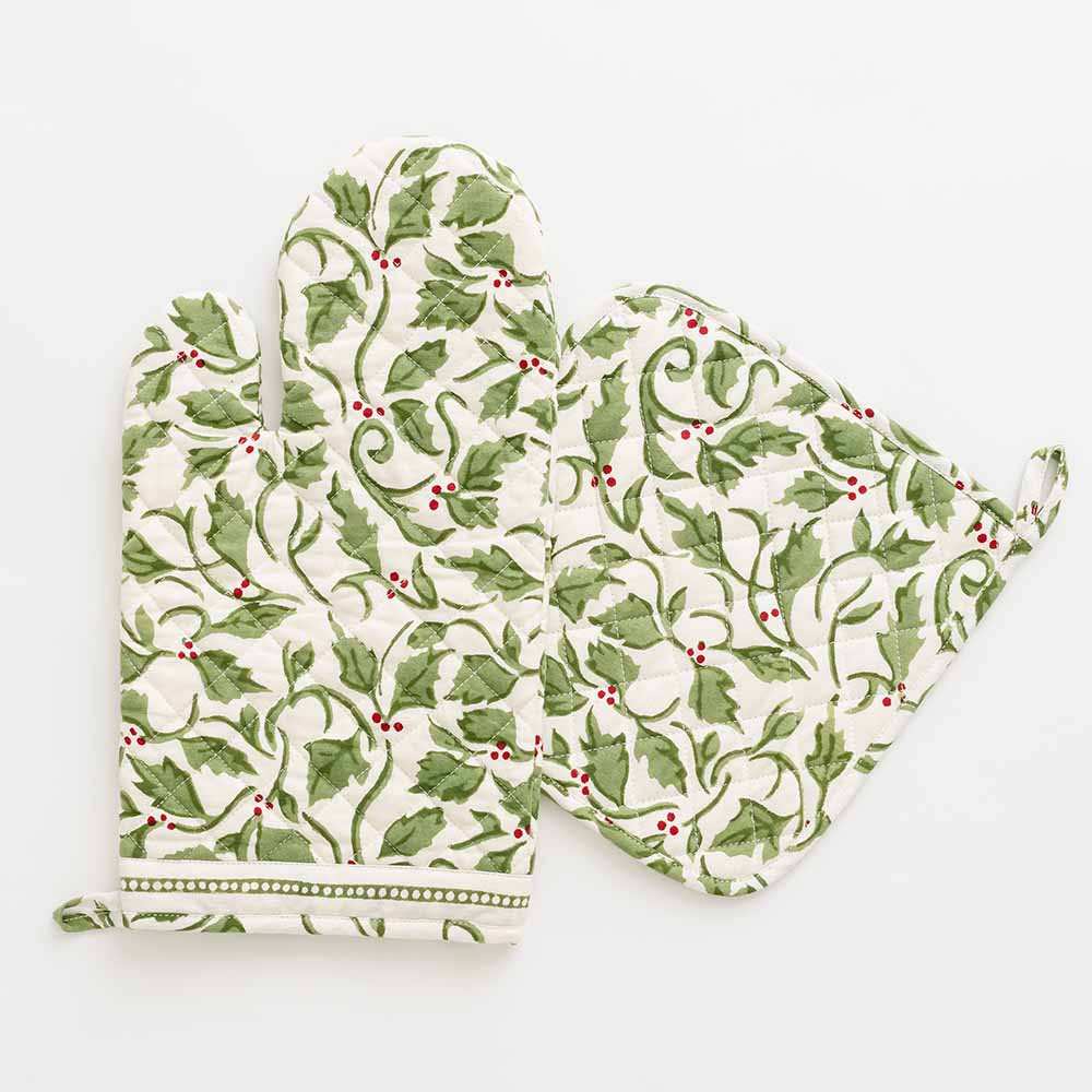 A pair of white oven mitts with a green and red holly berry pattern.