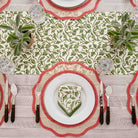 A table runner with a holly berry design on a wooden table with a dinner table setting