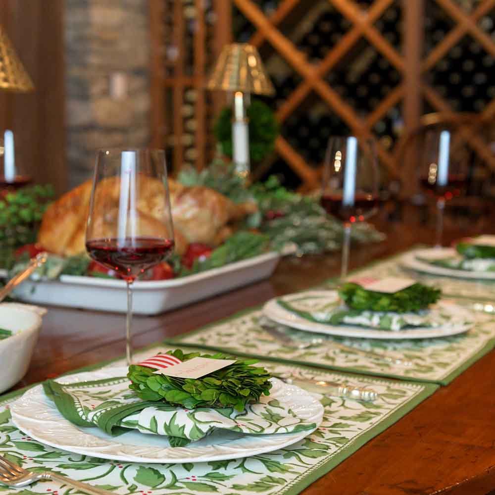 Cotton placemats with a Christmas holly and berries pattern displayed on a table setting