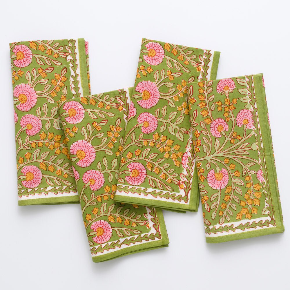 A set of four napkins with a floral pattern featuring pink flowers and green leaves displayed on a white background.