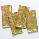 A set of four napkins with a floral pattern featuring pink flowers and green leaves displayed on a white background.