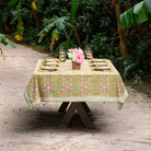 A tablecloth with a floral pattern featuring pink flowers and green leaves displayed on a table outdoors.