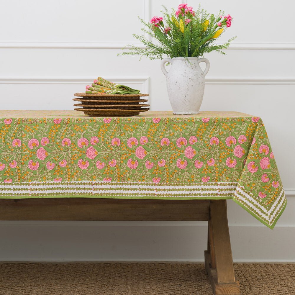 A tablecloth with a floral pattern featuring pink flowers and green leaves displayed on a white background.