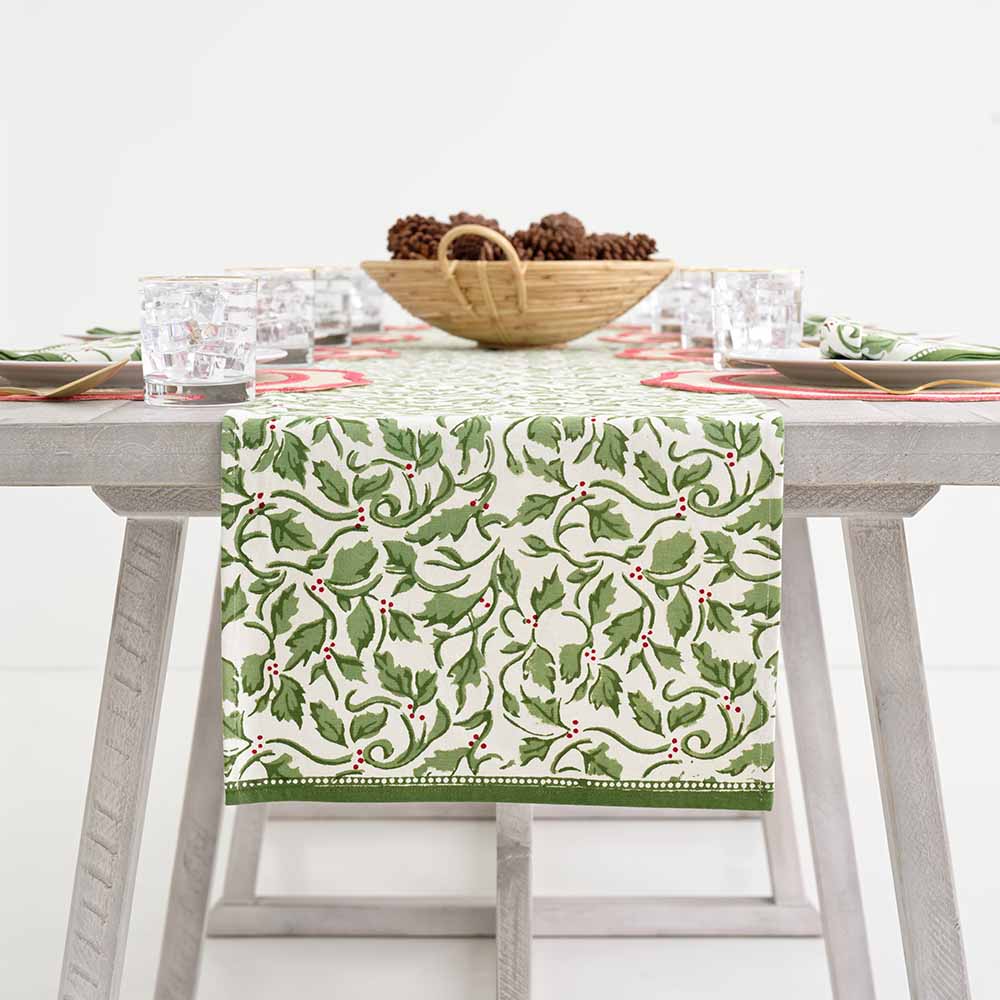 A table runner with a holly berry design on a wooden table